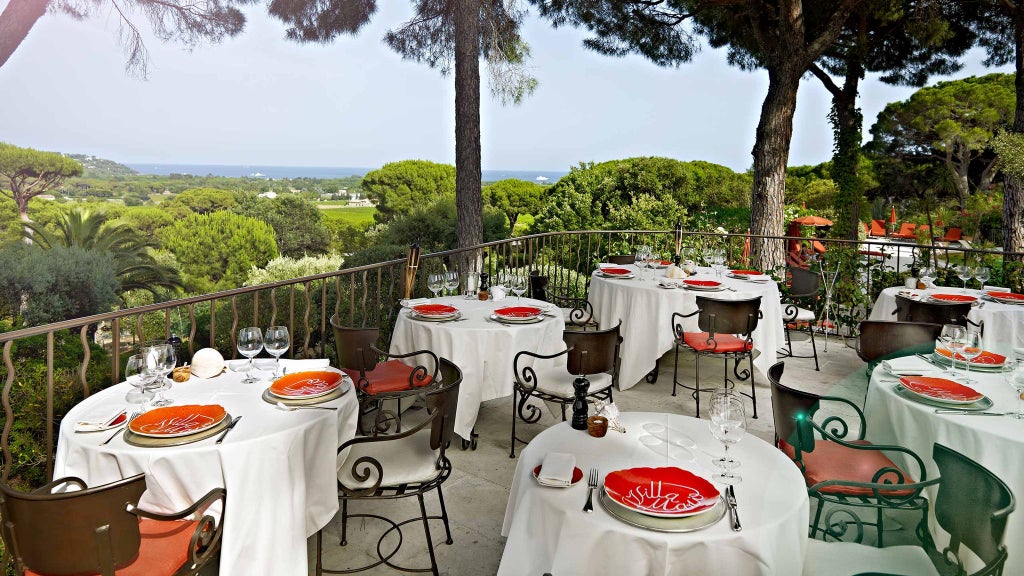 Luxurious poolside view of a Mediterranean-style villa hotel with azure pool, lush gardens, and elegant white architecture in Saint-Tropez