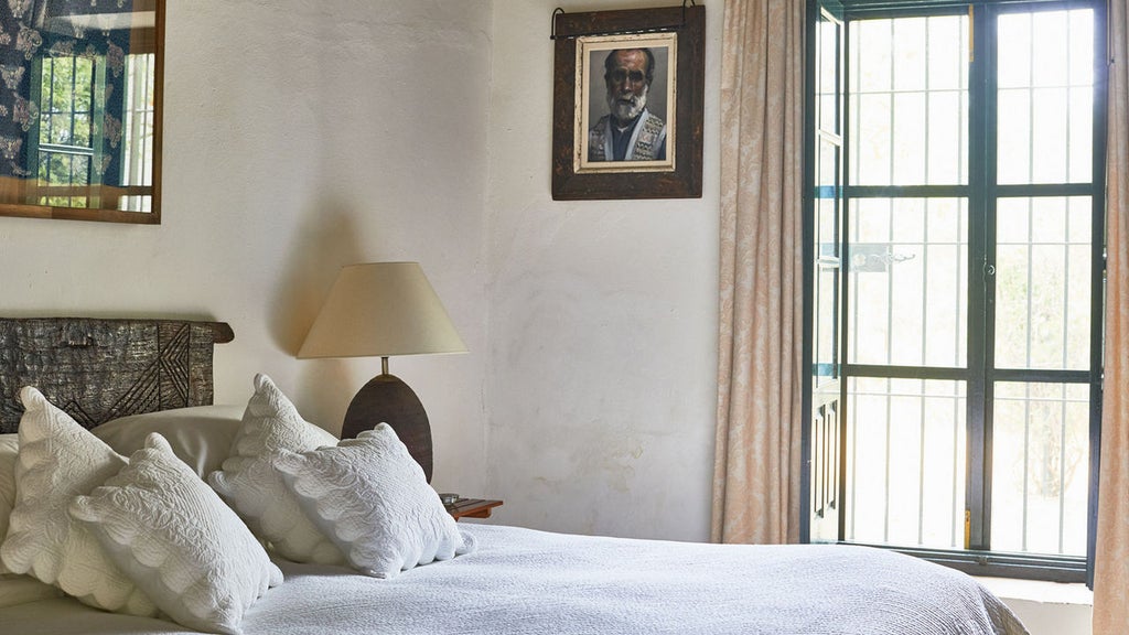 Historic Spanish luxury hotel with whitewashed walls, terracotta roof, and elegant courtyard featuring manicured gardens and stone fountain