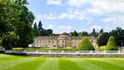 Luxurious [Hotel Name] nestled in scenic UK countryside, featuring elegant white Georgian architecture, manicured gardens, and grand exterior with symmetrical design