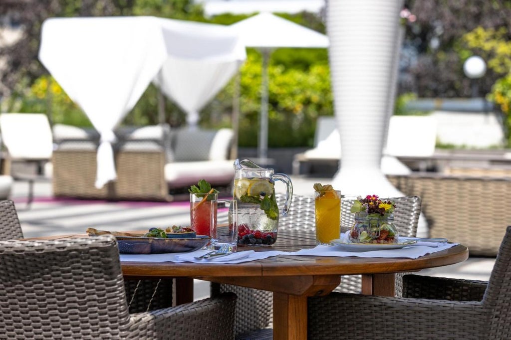 Majestic Belle Époque hotel with snow-capped Alps backdrop, grand white facade, ornate balconies, and perfectly manicured garden courtyard