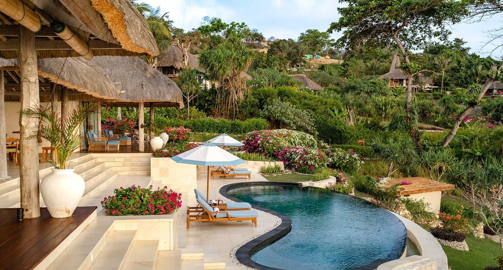 Luxurious open-air master bedroom in NIHI Sumba's Kasambi Estate, featuring traditional Indonesian design, ocean views, and elegant wood furnishings