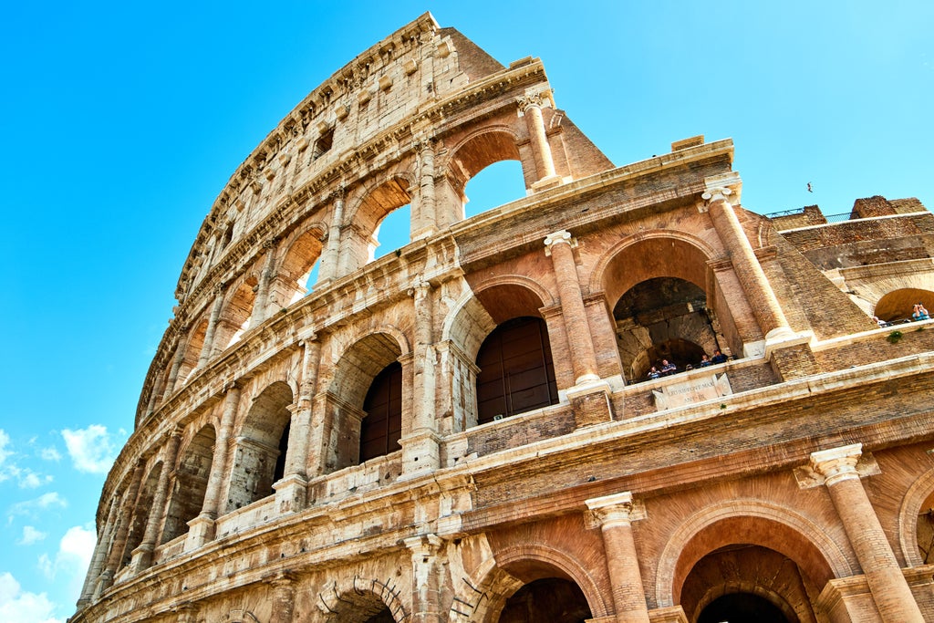 Ancient Roman Colosseum bathed in golden evening light, with exclusive VIP entrance and small tour group preparing to enter