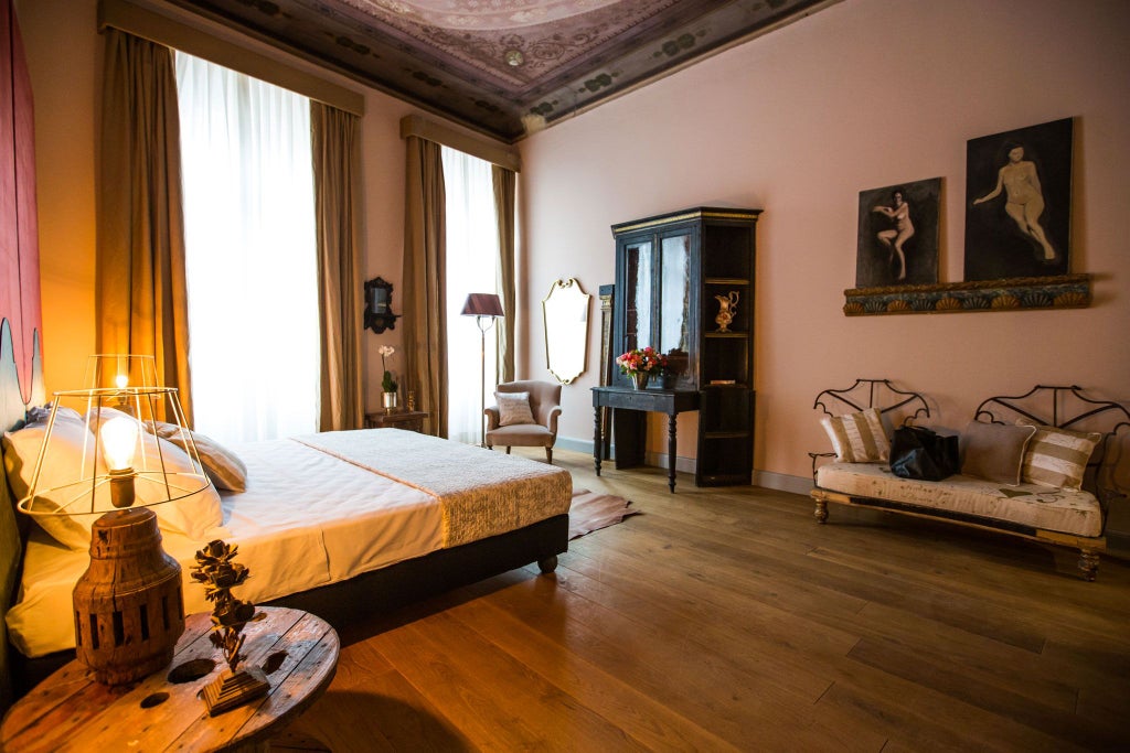 Elegant Tuscan-style deluxe room with ornate vintage furnishings, warm terracotta tones, antique wooden furniture, and soft luxurious bedding in Florence