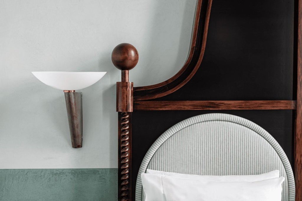 Elegant Italian hotel room with plush cream furnishings, vintage wooden headboard, and soft natural light filtering through tall arched windows