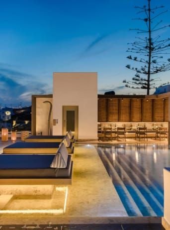 Luxurious whitewashed boutique hotel overlooking azure Aegean waters, with minimalist Cycladic architecture and chic sunbeds against stunning Mykonos landscape