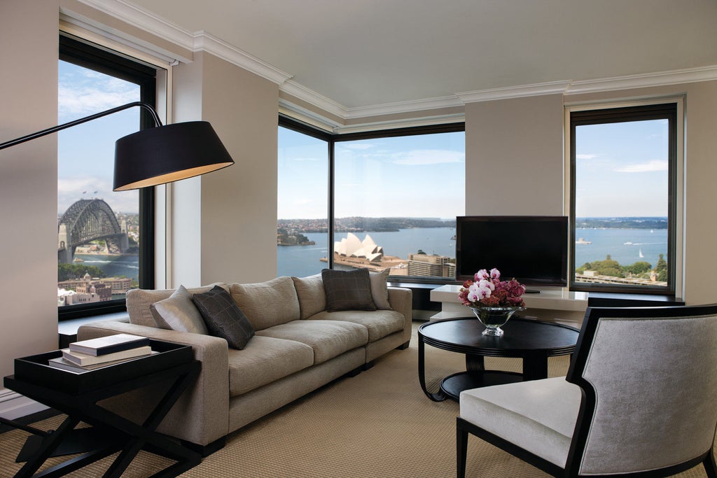 Modern luxury high-rise hotel overlooking Sydney Harbour, featuring glass facade, curved architecture and illuminated entrance at dusk