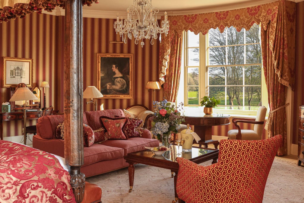 Spacious grand master suite at luxurious countryside hotel, featuring elegant four-poster bed, ornate furnishings, and classic British interior design aesthetic