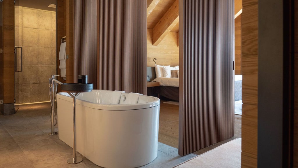 Luxurious Swiss alpine suite with wooden paneling, minimalist design, panoramic mountain view, and elegant king bed with crisp white linens at The Scenset Andermatt