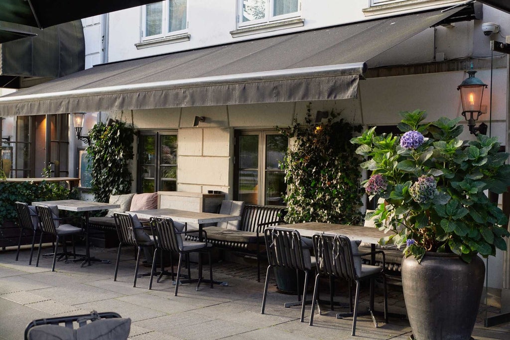 Elegant white historic hotel facade with Danish architectural details, nestled in a charming Copenhagen street with warm evening lighting