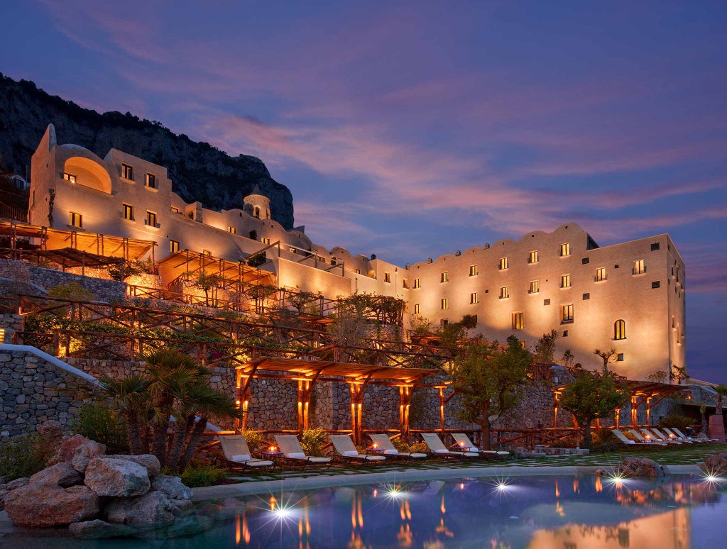 Luxury cliffside hotel Monastero Santa Rosa perched above Amalfi Coast, featuring terraced gardens and infinity pool overlooking Mediterranean Sea