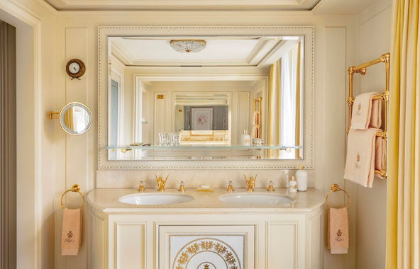 Opulent Deluxe Room at Ritz Paris featuring silk curtains, crystal chandelier, period furniture, and gold-framed artwork against cream walls