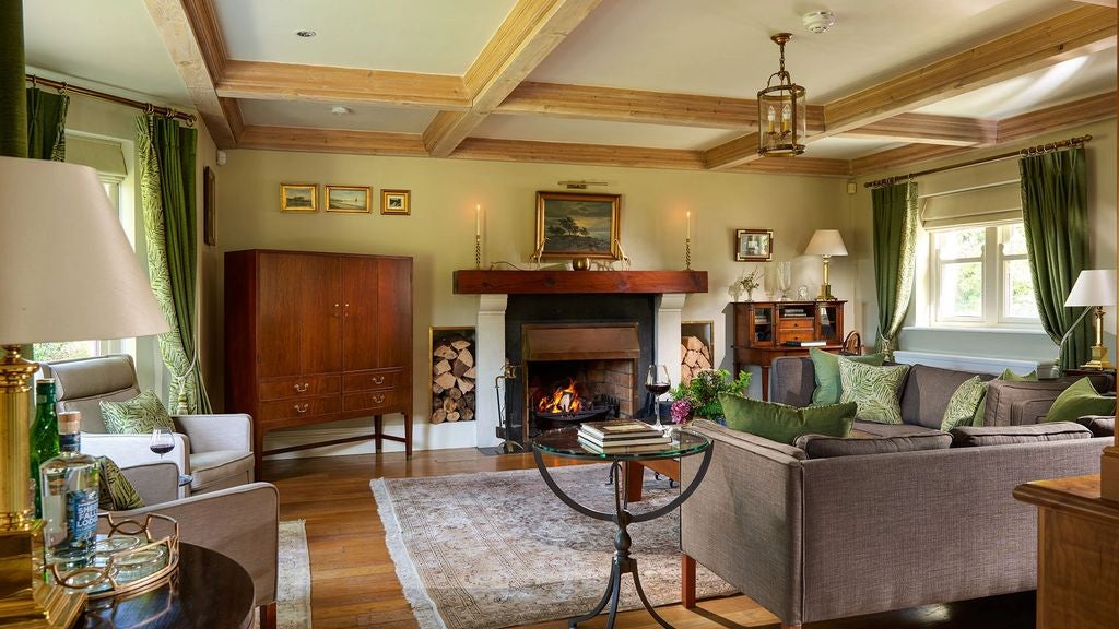 Bright, luxurious bedroom in Irish cottage with exposed wooden beams, plush king bed, antique furniture and countryside views