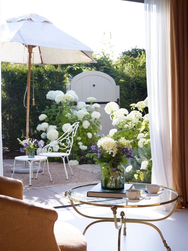 Luxurious garden-themed bedroom with soft botanical wallpaper, plush white linens, and elegant thyme-green accents in a serene UK boutique hotel setting