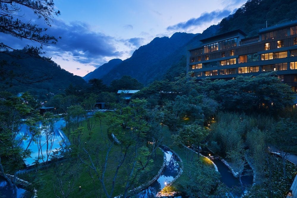 Traditional Japanese ryokan with wooden exterior and sliding doors, set against misty mountains, reflecting in a serene koi pond