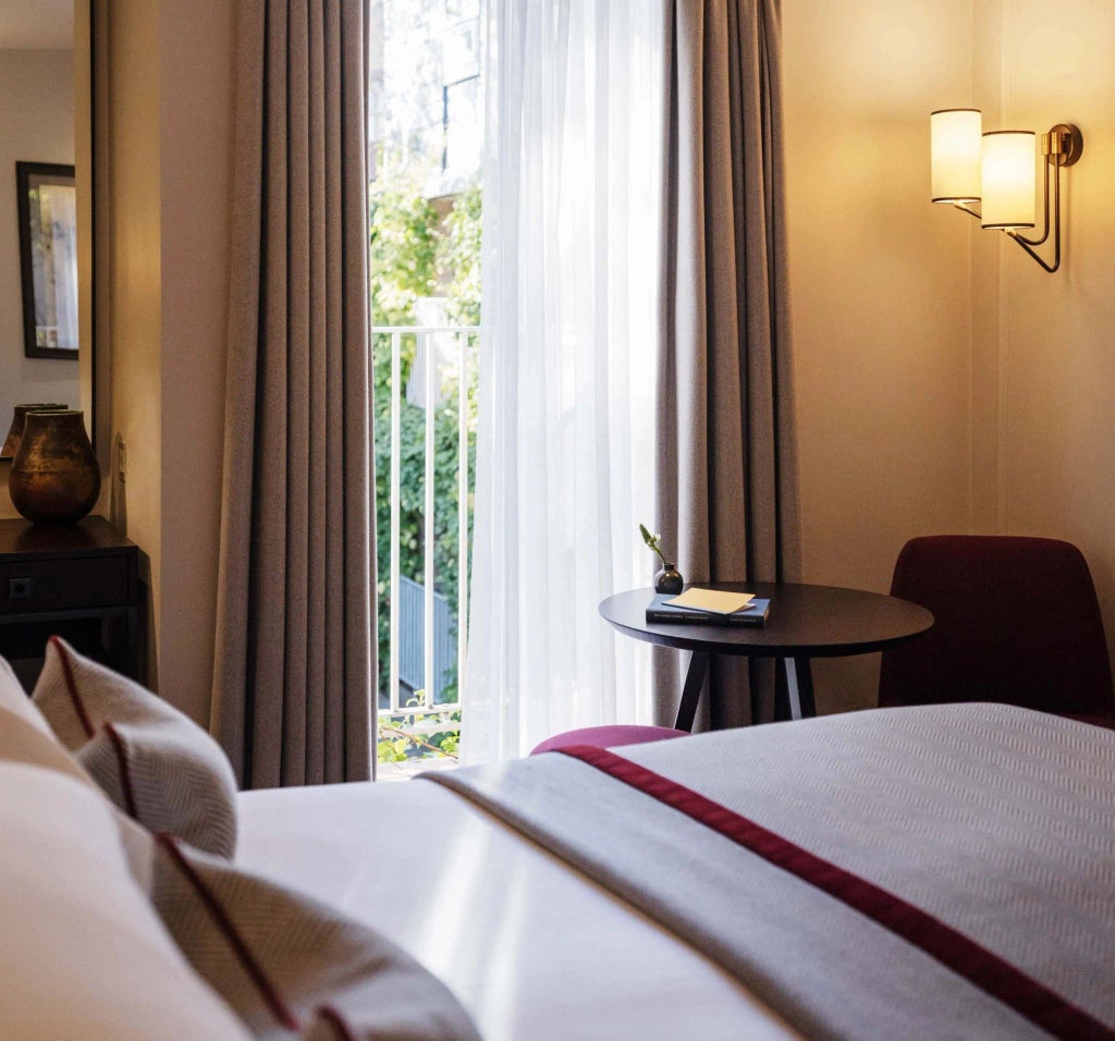 Elegant classic hotel room with crisp white linens, rich wooden furniture, soft neutral tones, and traditional British architectural details at scenset Old Parsonage Hotel