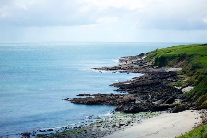 Luxurious coastal retreat with weathered driftwood exterior, nestled in scenic UK landscape, featuring elegant architecture and serene ocean backdrop