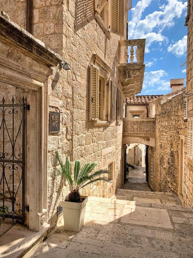 Historic stone palace hotel with sun-lit terrace overlooking Korčula's Adriatic coastline, featuring elegant outdoor lounge seating