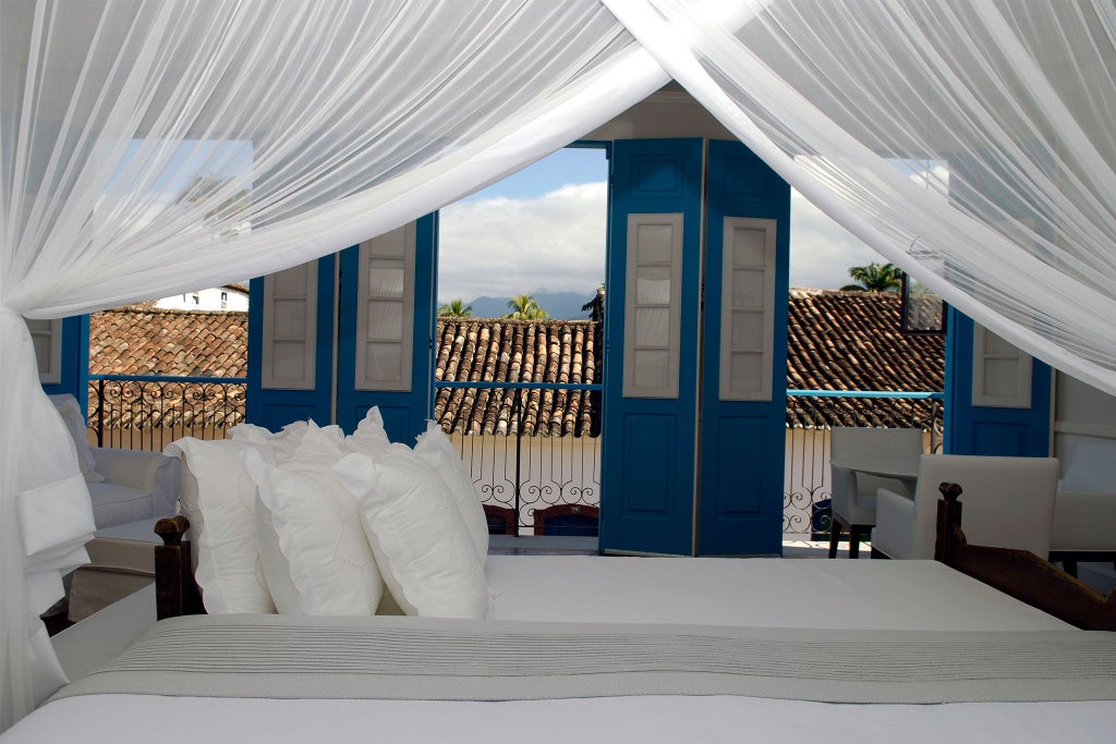 Elegant white-themed luxury suite at Casa Turquesa, featuring pristine white bedding, minimalist decor, and Brazilian coastal design elements