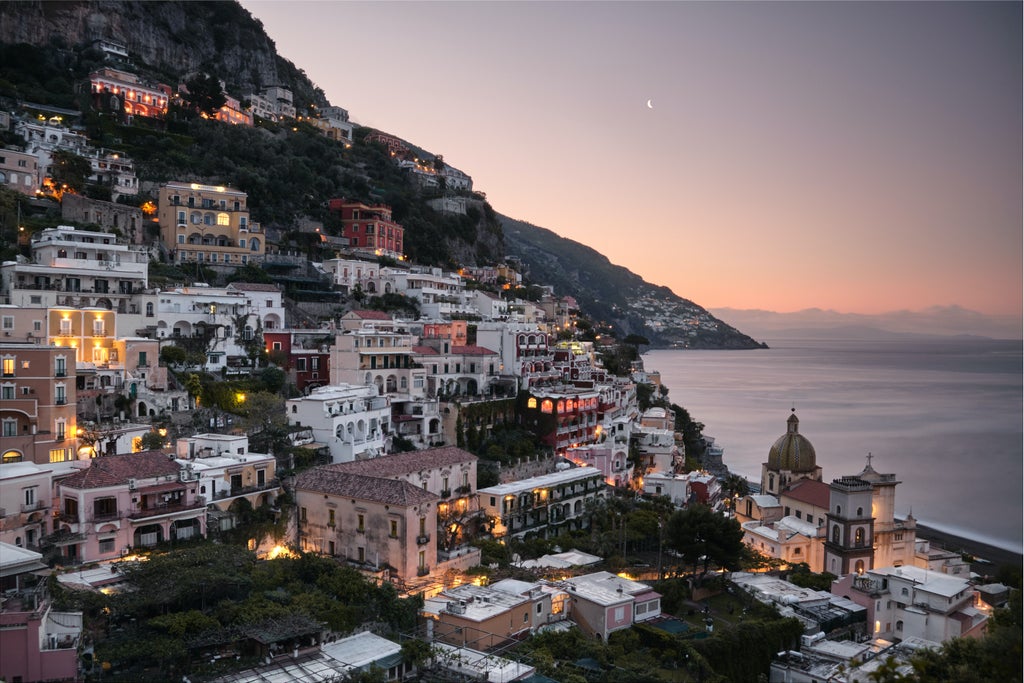 Luxury yacht gliding past colorful Italian villas perched on Amalfi Coast cliffs, turquoise Mediterranean waters sparkle in sunlight