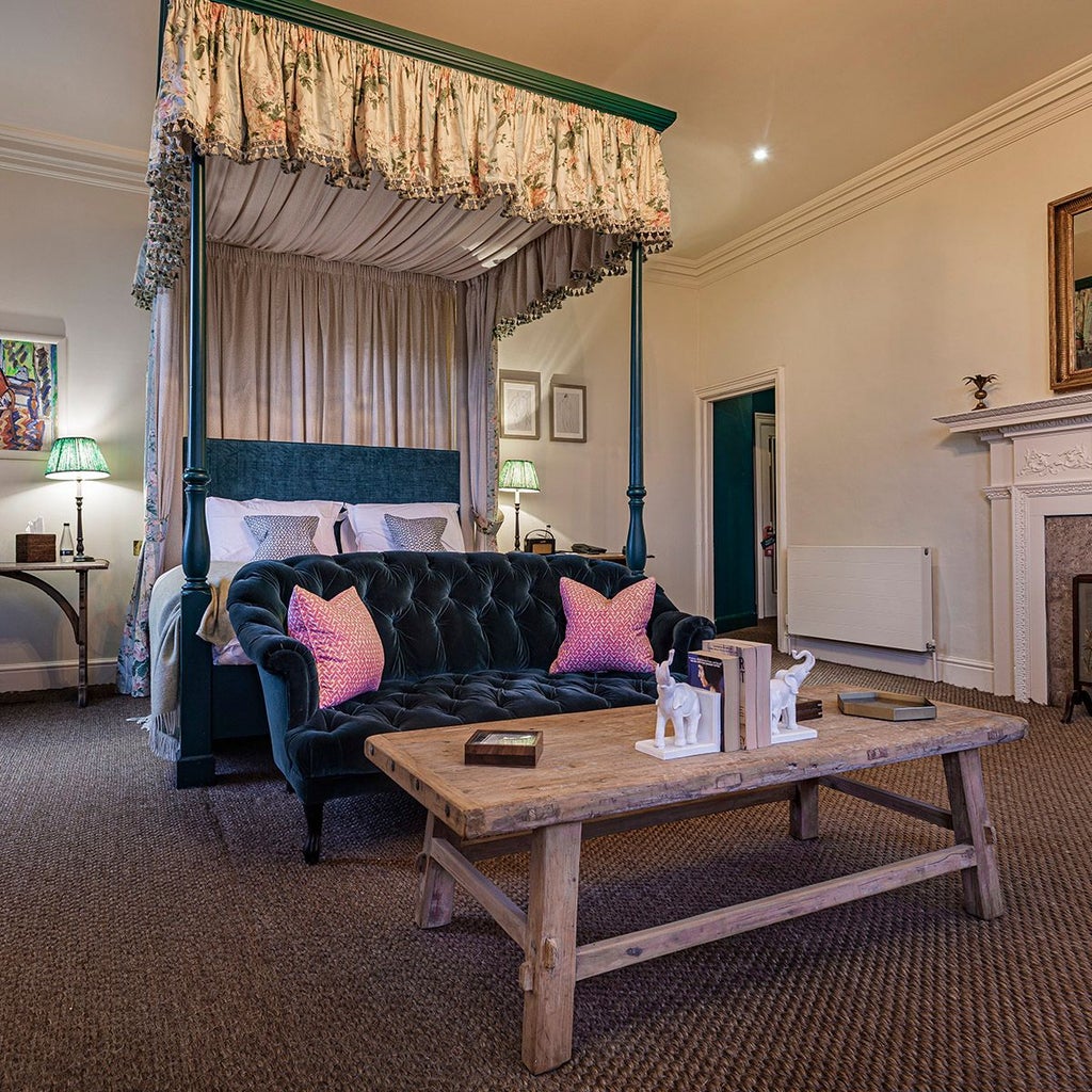 Elegant four-poster bed with rich wooden furnishings, soft neutral tones, and classic British design in a luxurious deluxe room at scenset hotel in the United Kingdom.