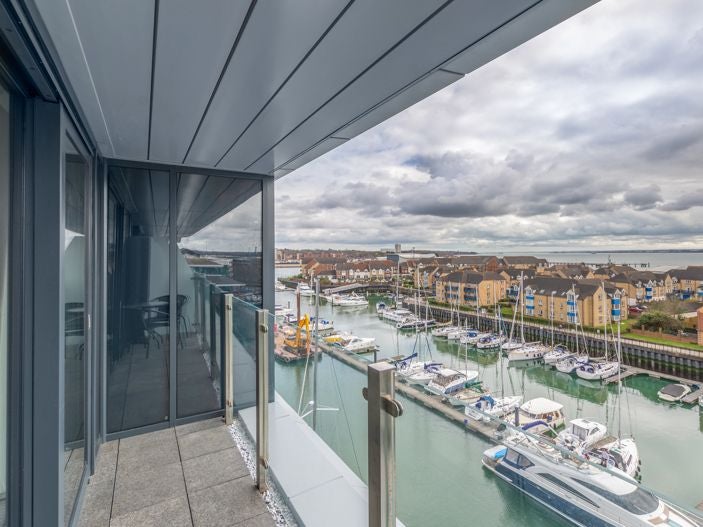 Elegant cosy double room at waterfront hotel with soft neutral decor, Juliet balcony overlooking Southampton's scenic harbour and modern furnishings