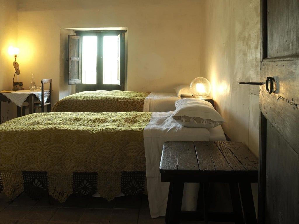 Rustic stone walls, antique wooden furnishings, and soft light streaming through a traditional window in a historic Italian hotel room overlooking a charming bell tower