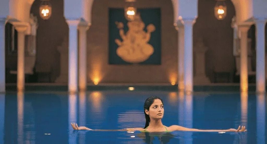 Elegant 5-star hotel with Mughal-inspired architecture featuring ornate domes, arches and fountains against Taj Mahal backdrop at sunset