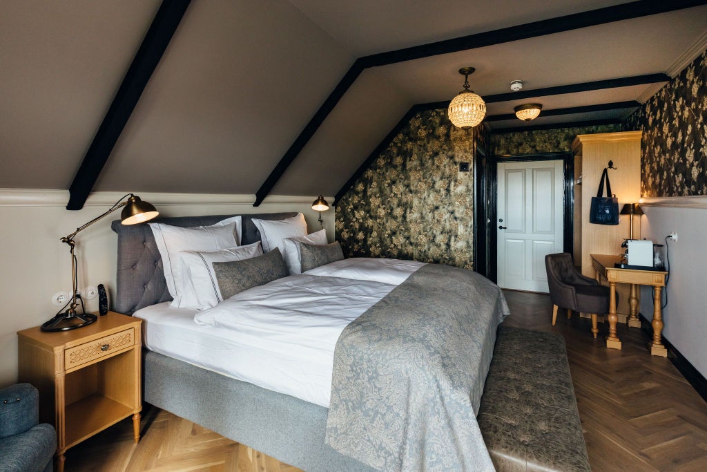 Cozy Icelandic hotel room with wooden furnishings, crisp white linens, and large window offering panoramic view of scenic landscape