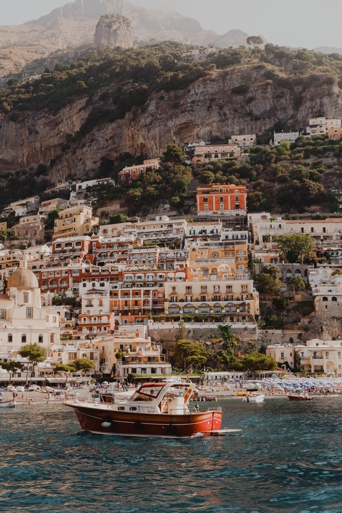 Scenic Amalfi Coast cliffside town with pastel-colored buildings cascading down to turquoise Mediterranean Sea, luxury yachts dotting harbor