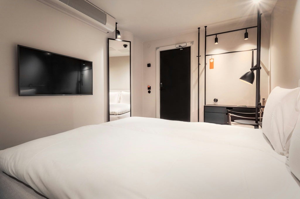 Minimalist Nordic hotel room with sleek grey furnishings, crisp white bedding, modern design, and soft ambient lighting in a sophisticated urban style