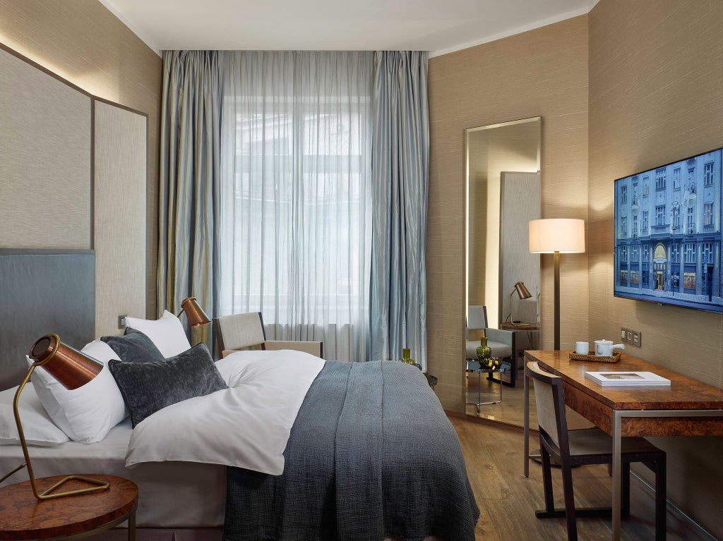 Luxurious king bedroom at scenset Hotel with elegant Czech design, plush bedding, modern amenities, and sleek city-view windows in Prague's downtown district