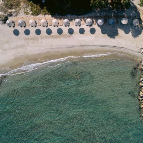 Modern white and blue Cycladic-style luxury spa hotel with minimalist architecture, overlooking the azure Aegean Sea, featuring clean lines and infinity pool at golden hour.