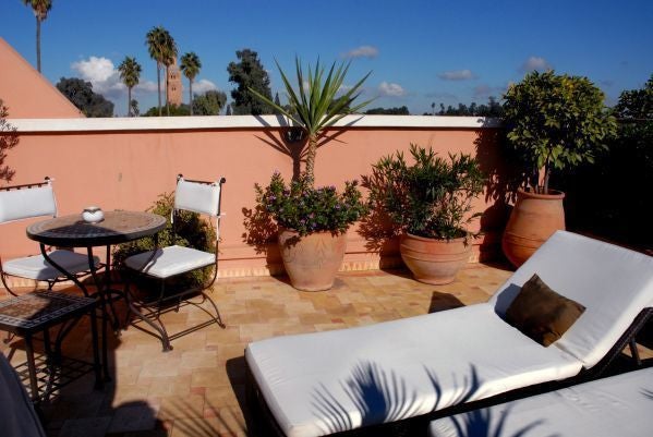 Luxurious Moroccan hotel room with ornate archways, elegant furnishings, private terrace, and traditional decor overlooking gardens