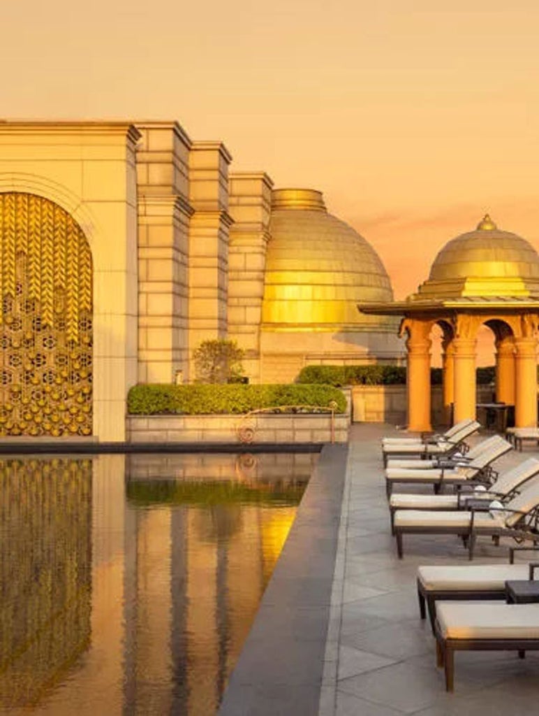 Opulent Leela Palace Jaipur hotel exterior with ornate Rajasthani architecture, golden sandstone facade, and manicured gardens at dusk