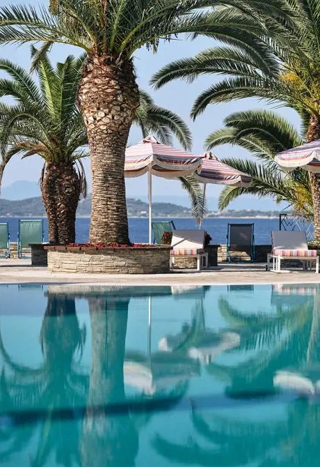 Luxurious seafront villas with private pools overlooking the Aegean Sea, set against a backdrop of white-washed architecture in scenic Greek landscape.