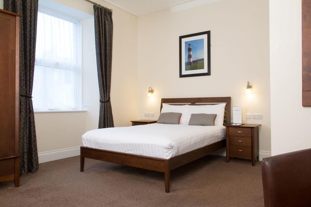 Elegant double room at The Scenset Plymouth hotel, featuring plush white bedding, modern decor, large window with city view, and sophisticated neutral color palette