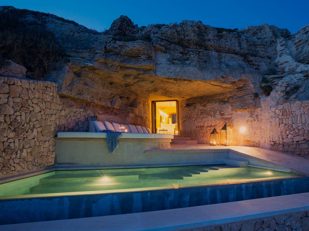 Luxury Spanish fortress hotel Cap Rocat with stone archways and terrace overlooking Mediterranean Sea at sunset, built into cliffside