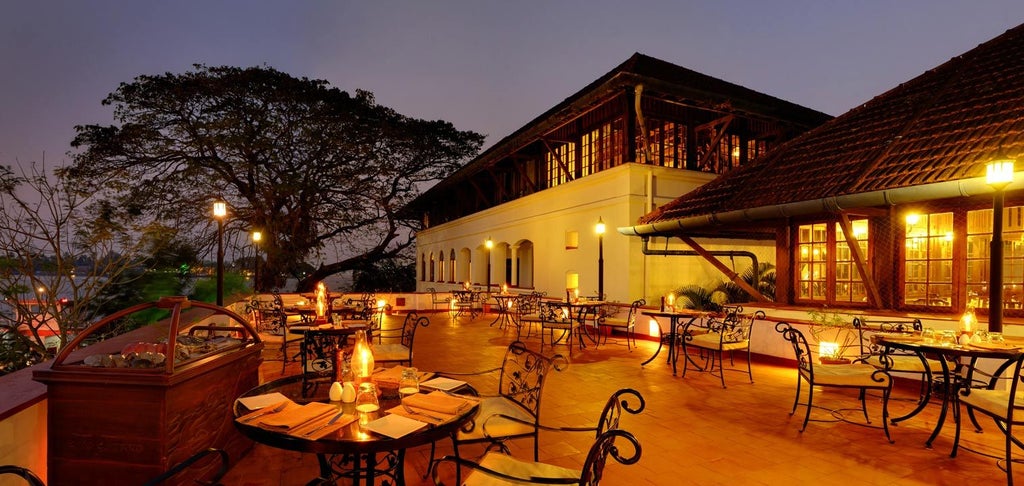 Historic colonial-style hotel in Fort Kochi with waterfront terrace, white facades, traditional wooden windows and harbor views