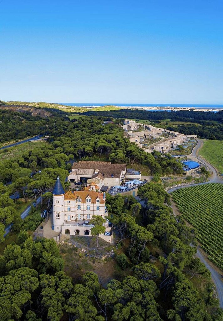 Elegant French countryside château with stone walls, manicured gardens, lavender fields, and terracotta roof set against a golden sunset backdrop.