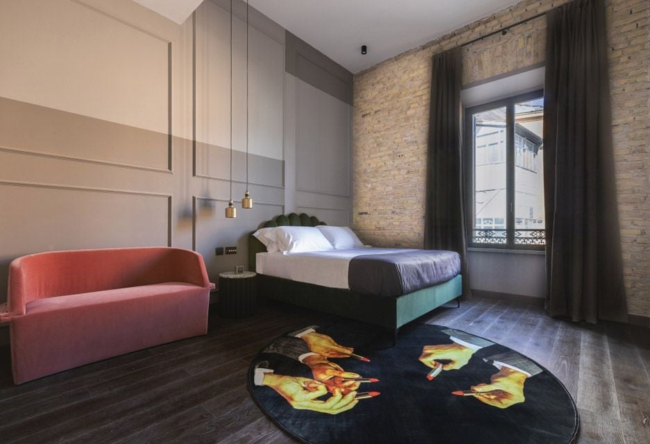 Elegant double hotel room with modern design, soft neutral tones, plush white bedding, sleek furniture, and warm ambient lighting in Chapter Roma hotel.