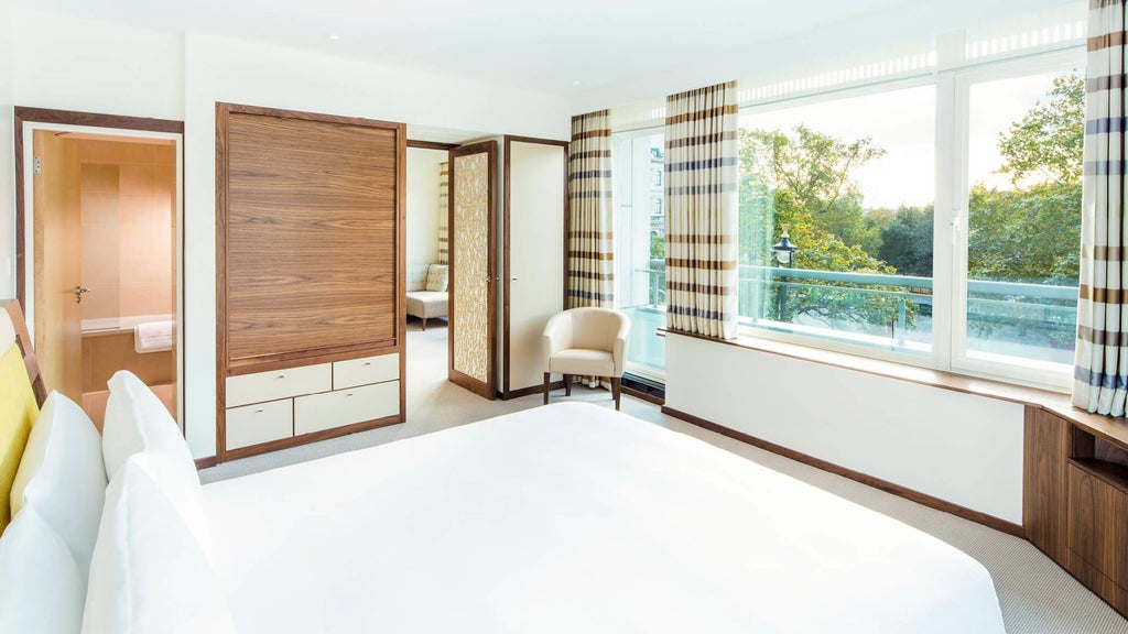 Elegant COMO Suite with plush white bedding, contemporary design, and city views at COMO Metropolitan London, showcasing minimalist luxury and refined hospitality