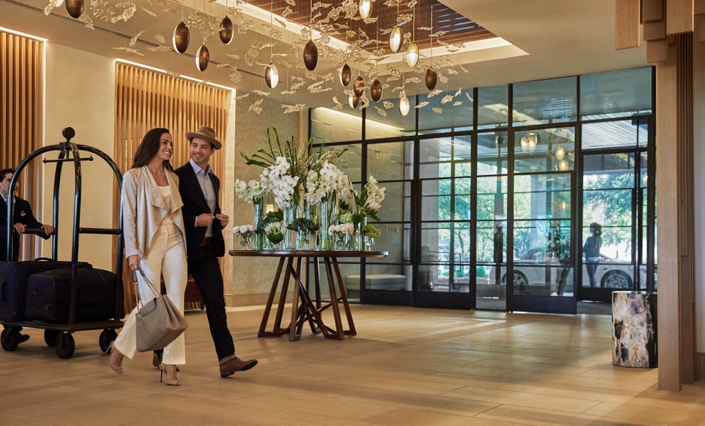 Elegant Four Seasons Austin hotel exterior with glass-clad facade reflecting sunlight, lush gardens, and Lady Bird Lake views at dusk