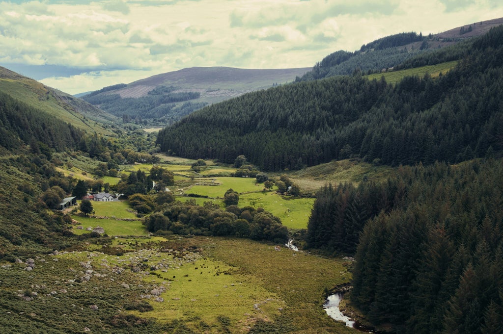 Lush green rolling hills of Wicklow, ancient stone walls, misty mountains, elegant travelers exploring historic landscape with verdant countryside and dramatic Celtic scenery