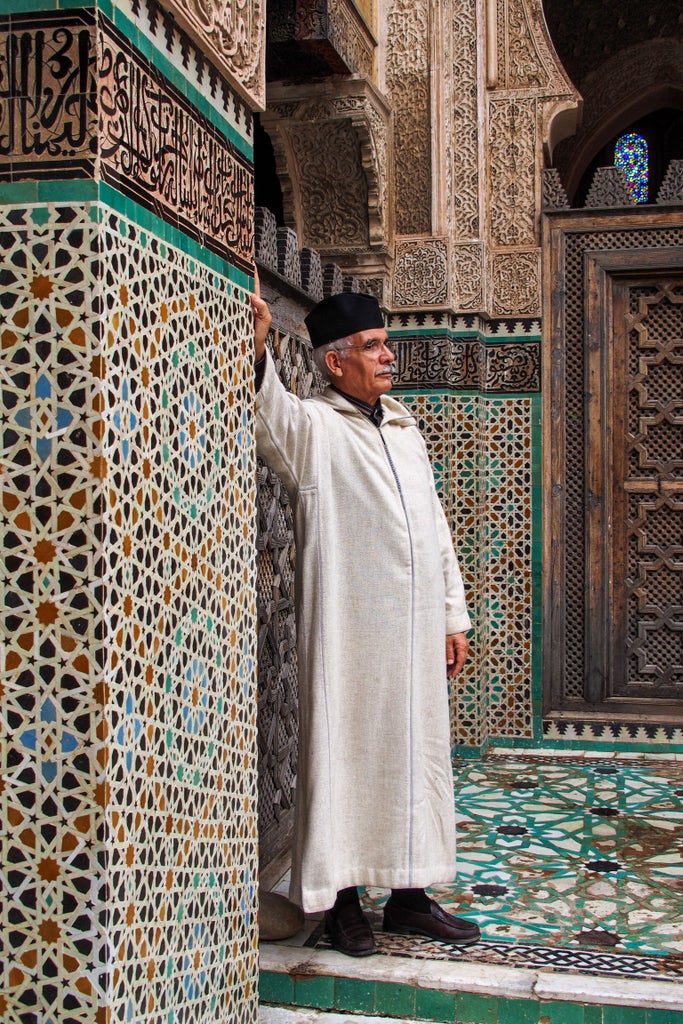 Ancient copper lanterns illuminate narrow cobblestone alleys in Fez's medina quarter, with ornate Moorish doorways and vibrant textiles