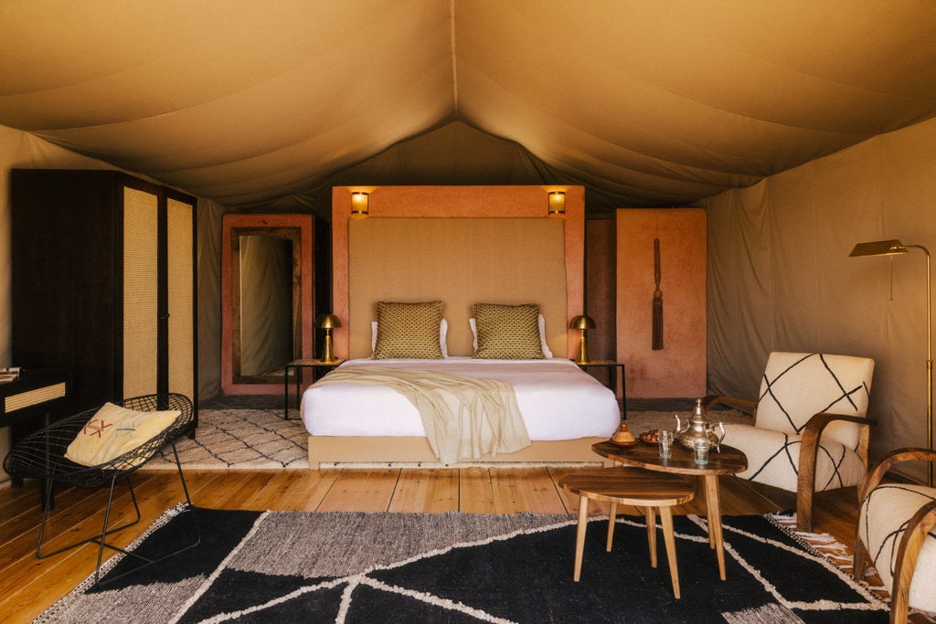 Luxurious desert lodge tent with private terrace overlooking Atlas Mountains, featuring modern furnishings and natural textures