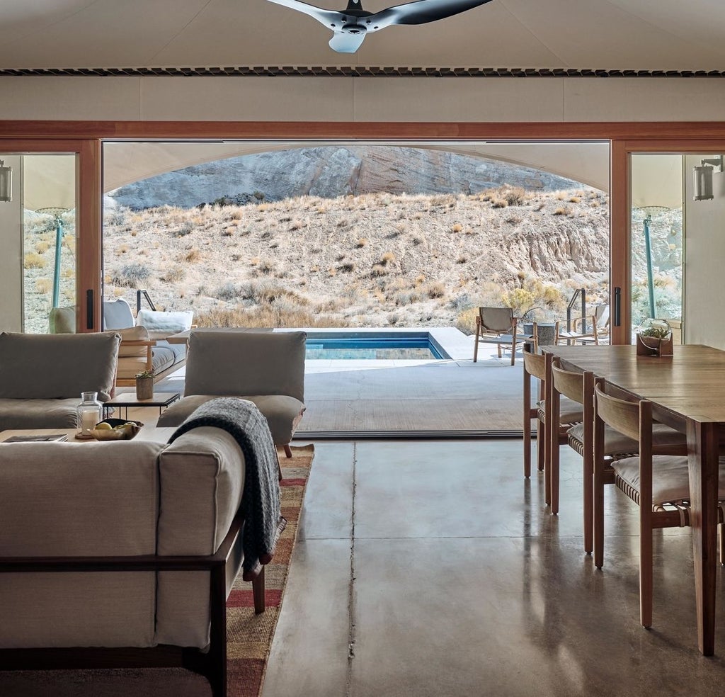 Modern concrete resort seamlessly blends into desert landscape, featuring infinity pool and private terraces against red rock canyon walls