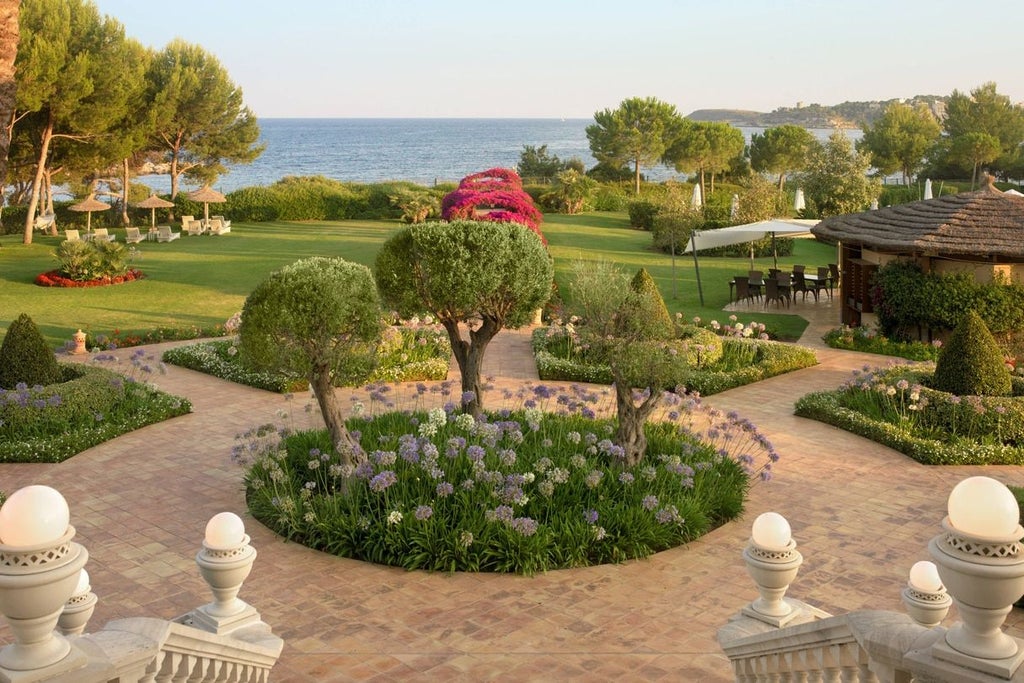 Mediterranean luxury resort with tiered terraces, palm trees and elegant pools overlooking the turquoise sea at sunset in Mallorca