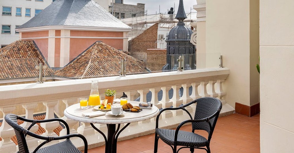 Elegant deluxe terrace room at The Principal Madrid hotel with sleek modern decor, plush furnishings, and panoramic city views of scenic Spanish architecture