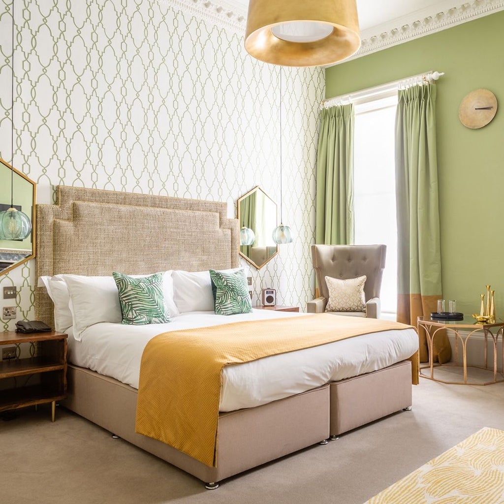 Elegant junior suite with plush king bed, soft neutral tones, contemporary designer furniture, and large windows overlooking urban landscape in United Kingdom.