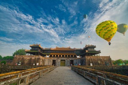 Elegant colonial-style hotel exterior with French architectural influences, lush tropical gardens, and pristine white facade in historic Hue, Vietnam